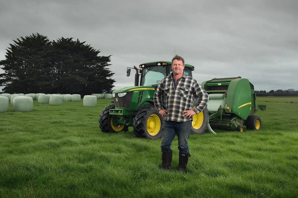 Southland agricultural contractor standing beside a tractor and baler on a farm near Winton